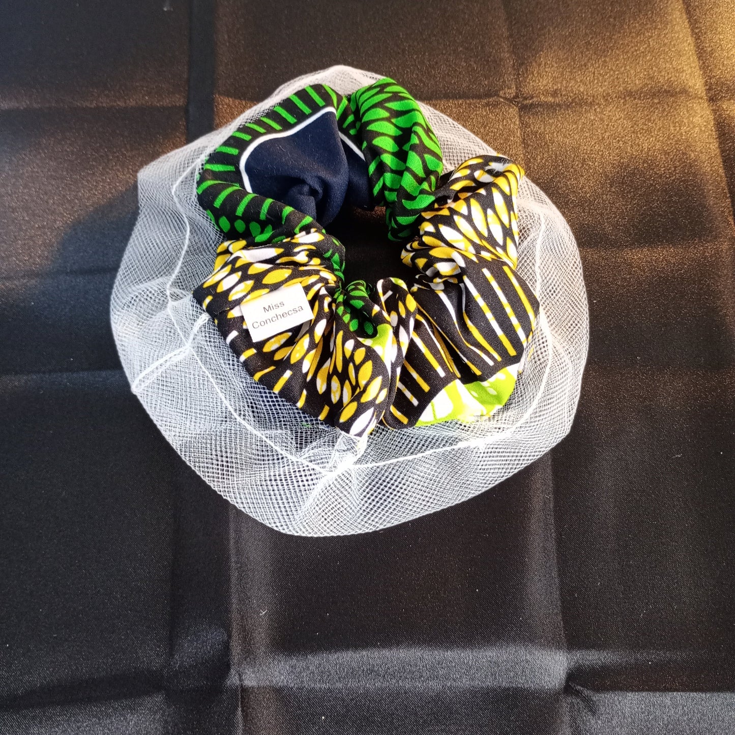 Three colorful Ankara scrunchies with white mesh.